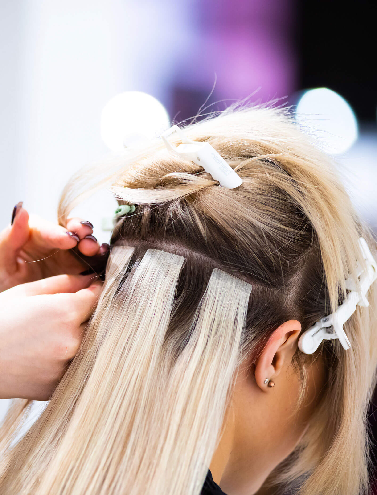Extension capelli - donna di lato con capelli biondi e mollette da parrucchiere - Haarstudio Mayr a Brunico