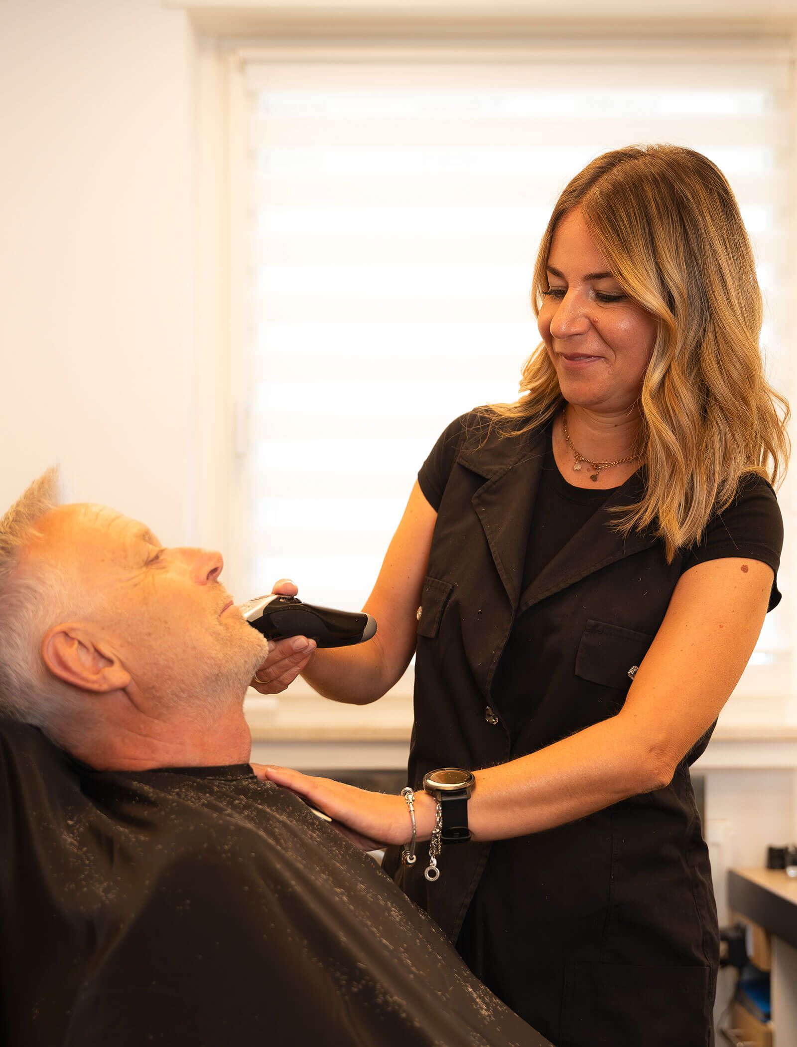 Impiegato - donna che rade la barba a un cliente - Haarstudio Mayr a Brunico